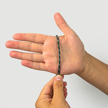 Hand wird an der breitesten Stelle ohne Daumen mit einem Stück Garn umwickelt.